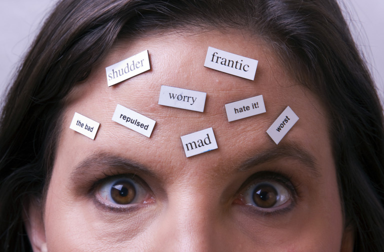 Magnet words on female's forehead. Words are all negative. Implies Negative Thoughts